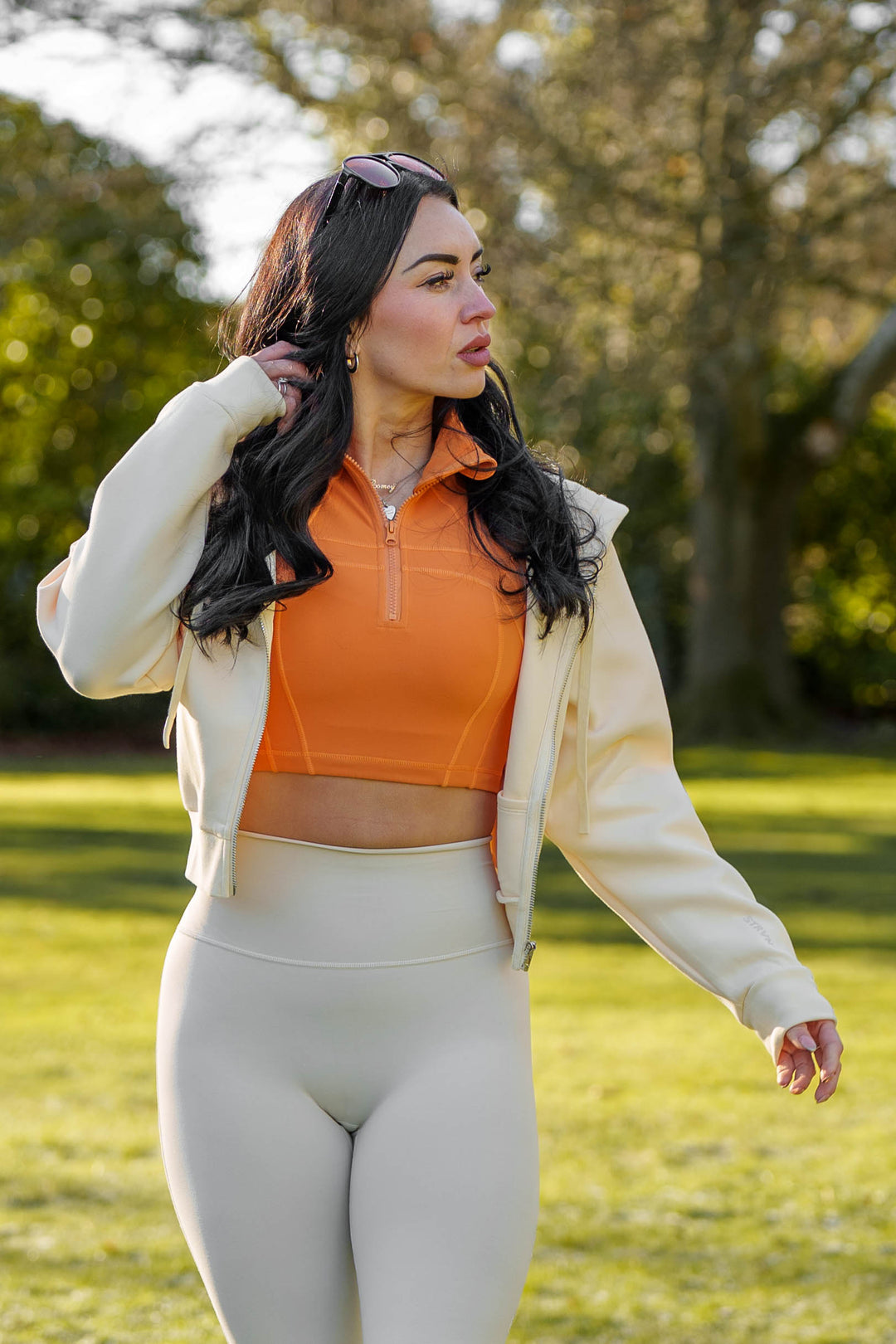 Cream Cropped Zip Hoodie worn open over an orange top by Nicole