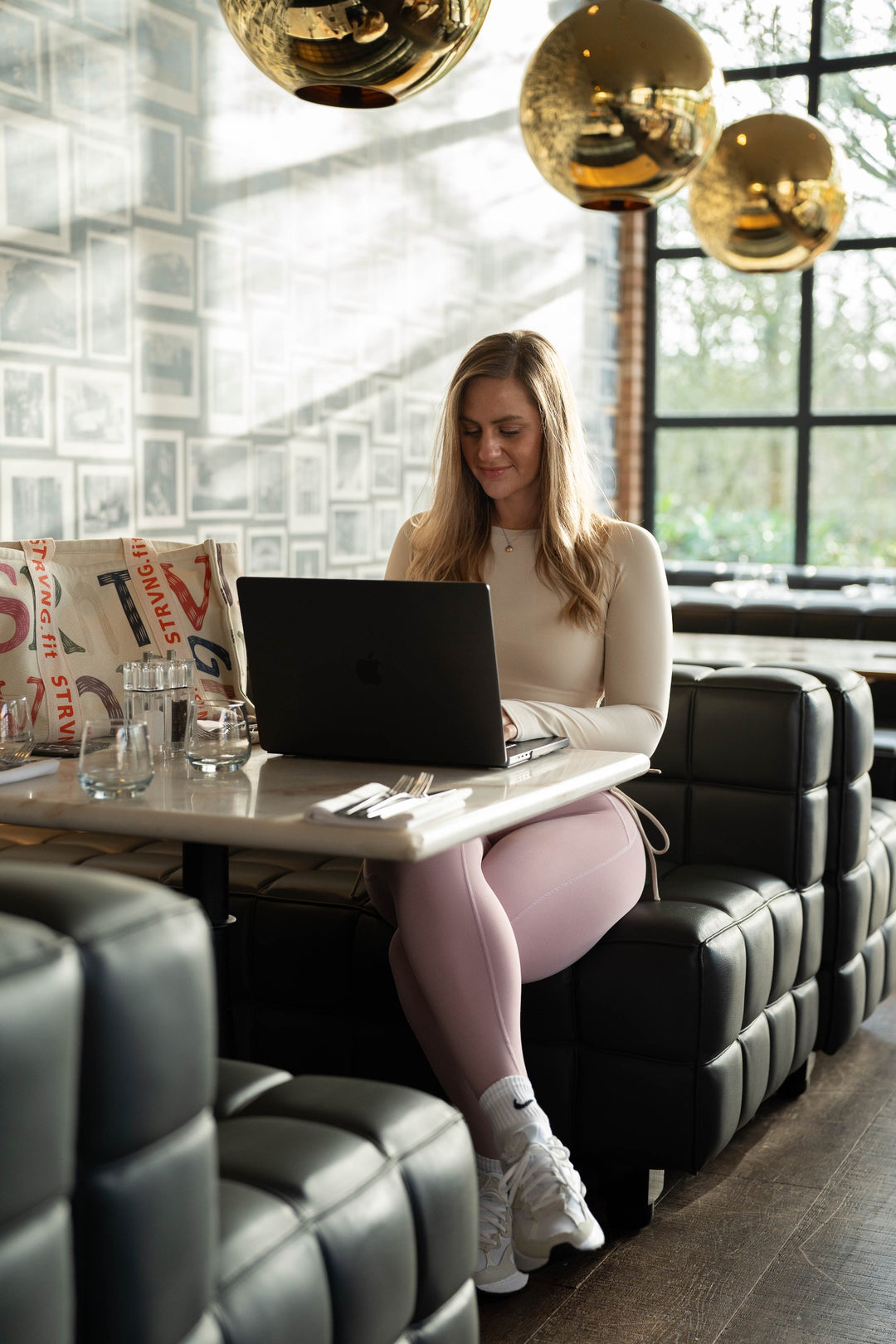 Becky wearing the Beige Motion Ruched Top while working at a cafe